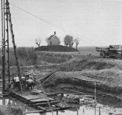 April 1936, Werkelozen werken aan een brug over het Gat van den Noorder Els. Op de achtergrond nog een oude griendheuvel met keet. Maker foto bij de redactie onbekend.